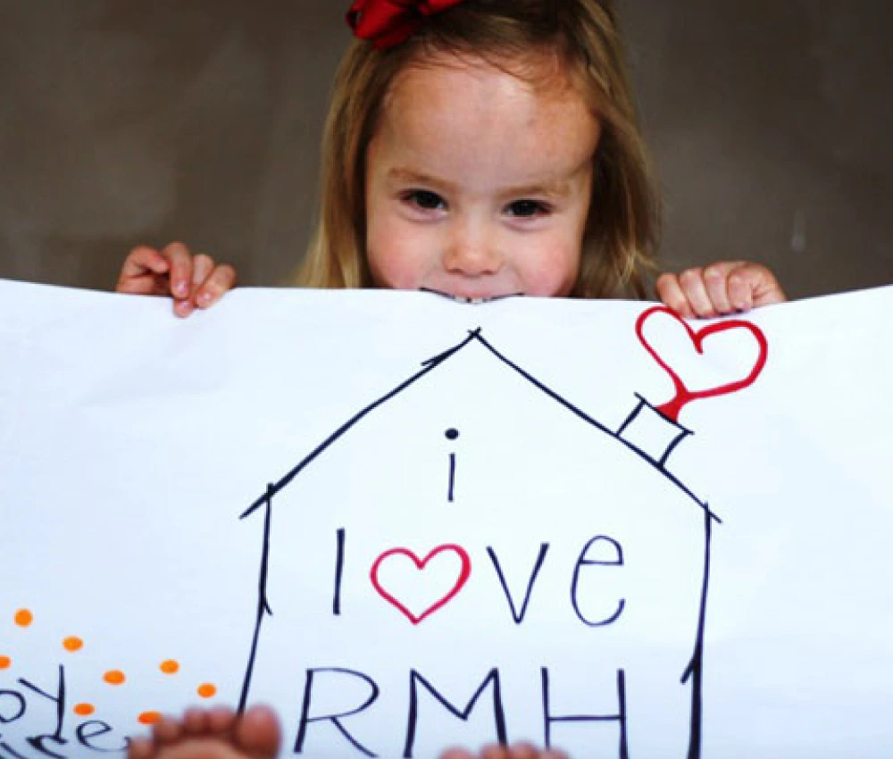 Young girl holding up large sign that reads "I Love RMH"
