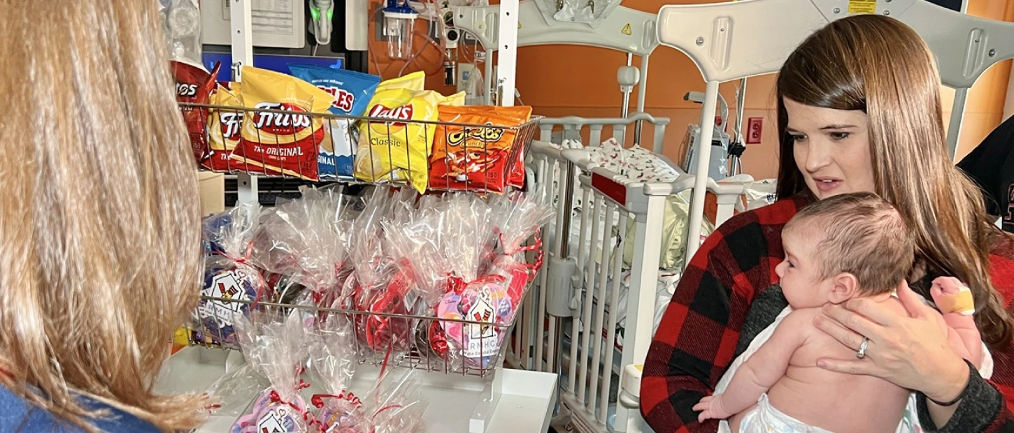 mother holding newborn baby and picking out gifts and snacks from our hospitality cart