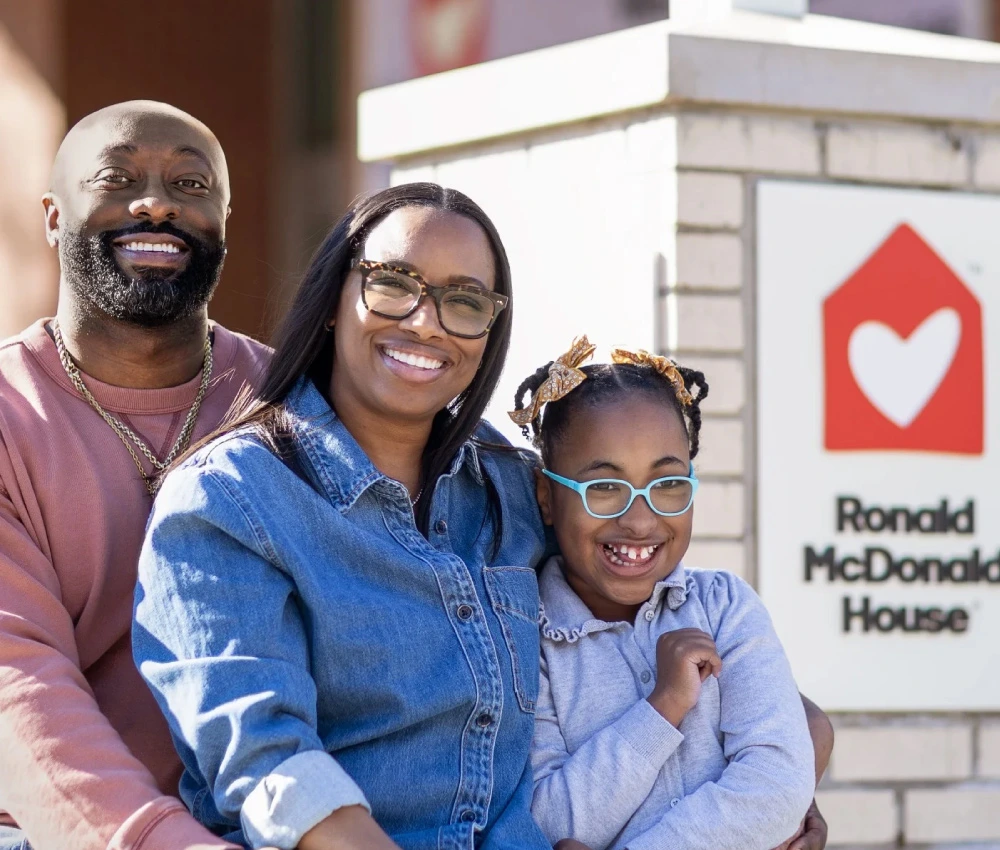 McBride family sitting next to Ronald McDonald House signage