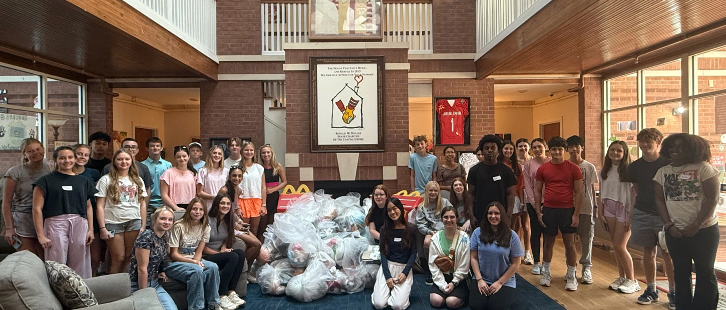 large group of teenage volunteers with a large gathering of collected donated goods
