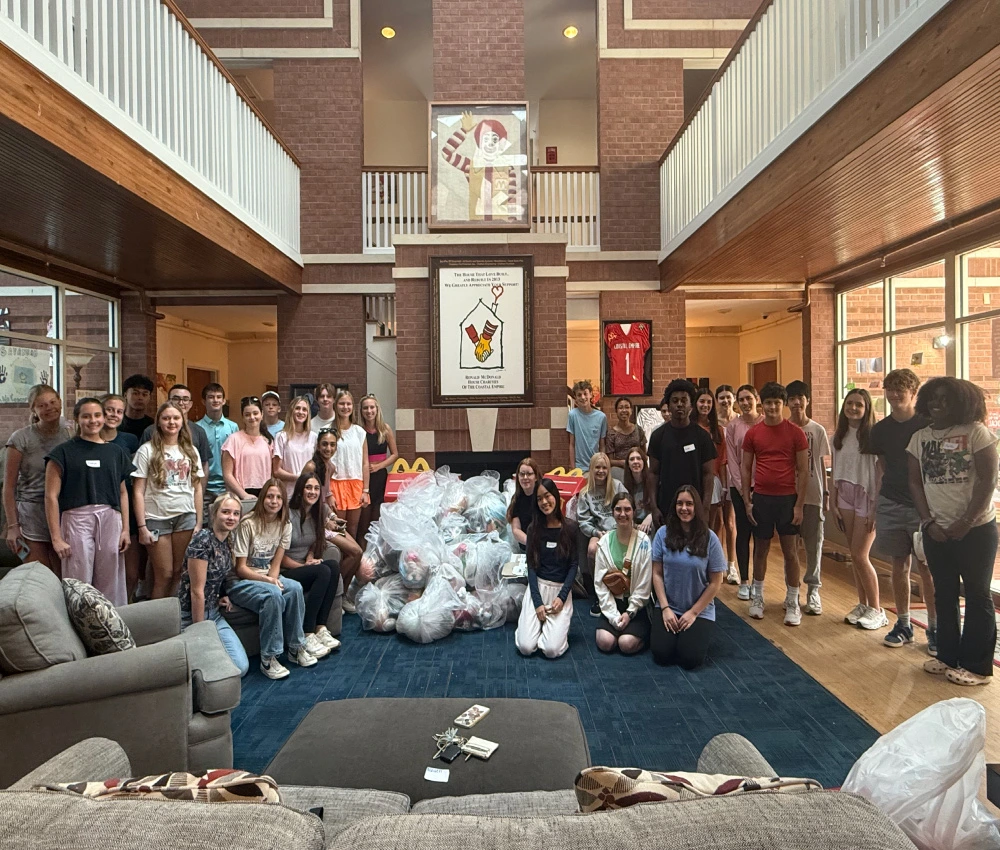 large group of teenage volunteers with a large gathering of collected donated goods